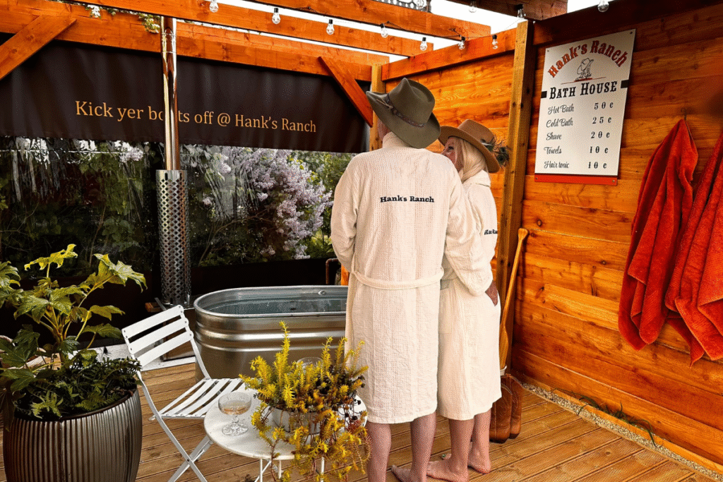 couple in Hank's Ranch dressing gowns with cowboy hats next to tin bath